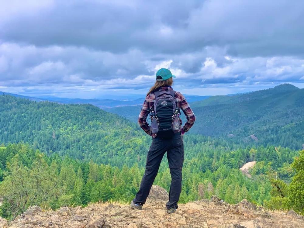 A woman on a hike looking at the forest from on top of Mount St. Helena