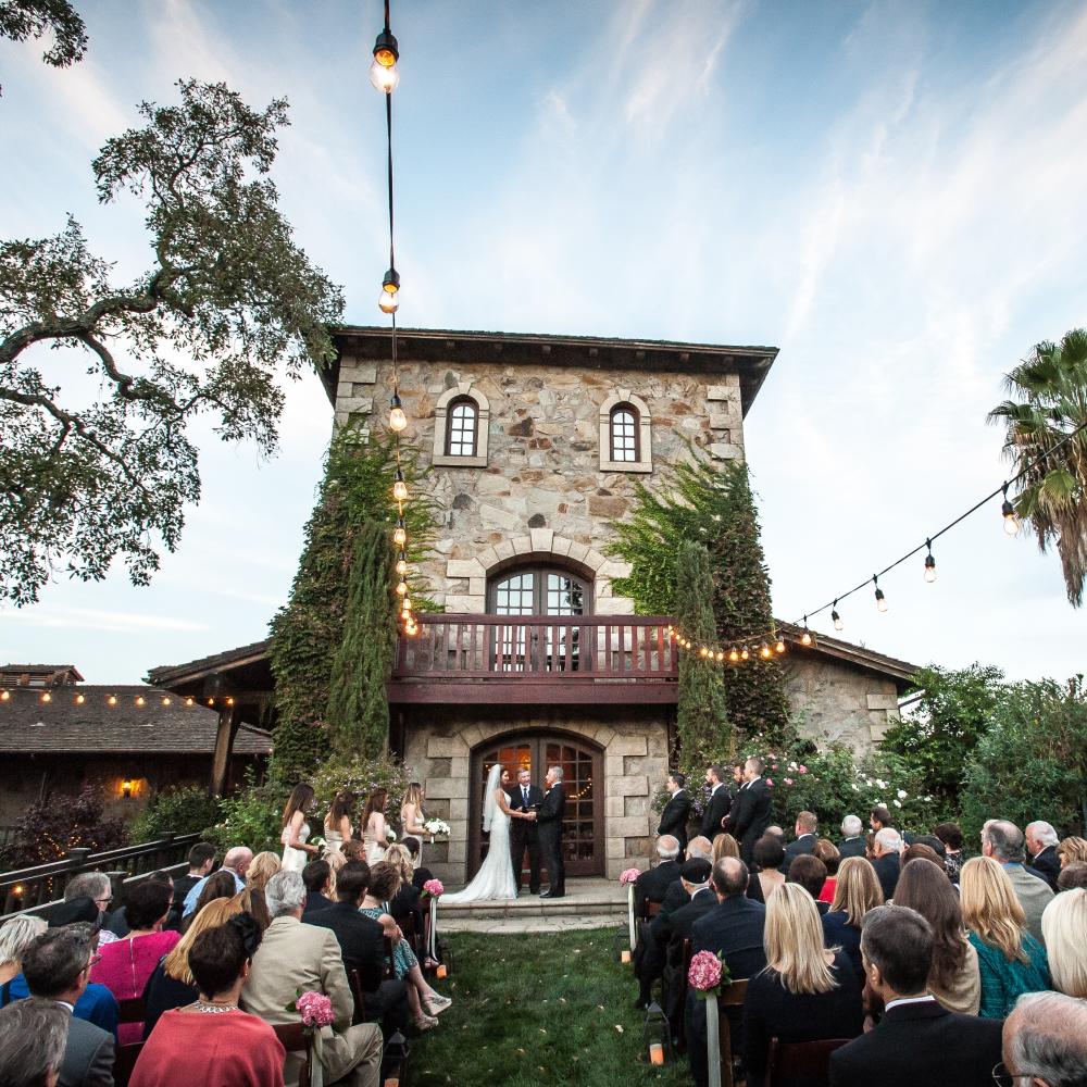 Man and woman standing at alter in front of the doors to a winery with guests